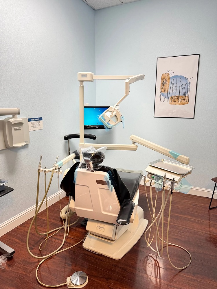 A dental operatory room featuring a professional patient chair, overhead lighting, and medical equipment against light blue walls