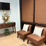 Two brown leather chairs with white pillows sit next to a wooden console table decorated with a large floral arrangement and a wall-mounted TV